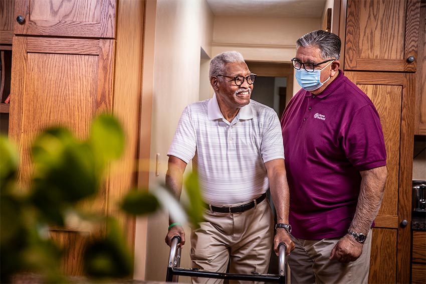 Caregiver providing care and supervision to an elderly man in his home.