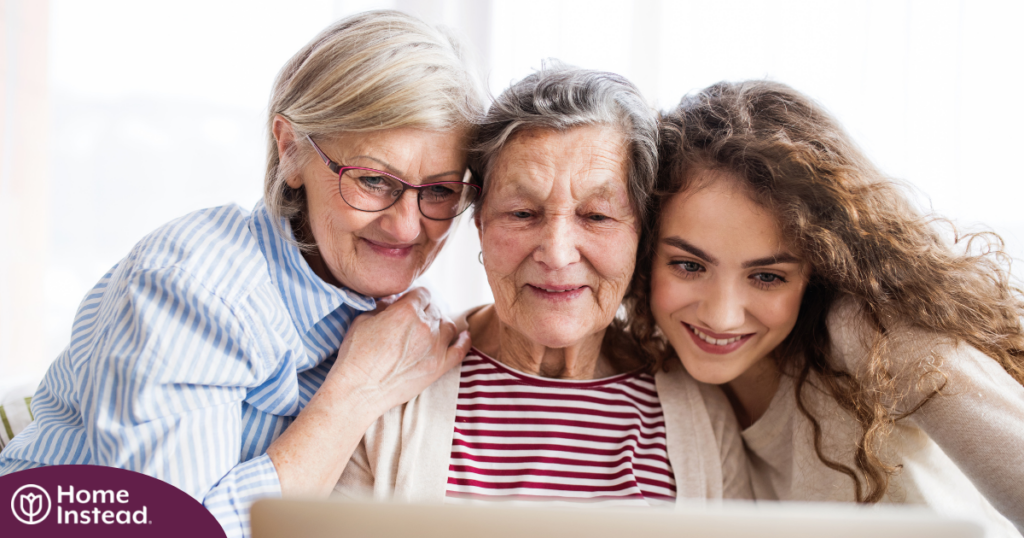 Three generations embrace and look at a computer, representing the sandwich generation.