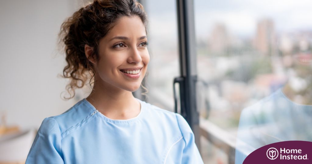 A woman in scrubs smiles, representing the satisfaction that can come with transitioning into a professional caregiving career.